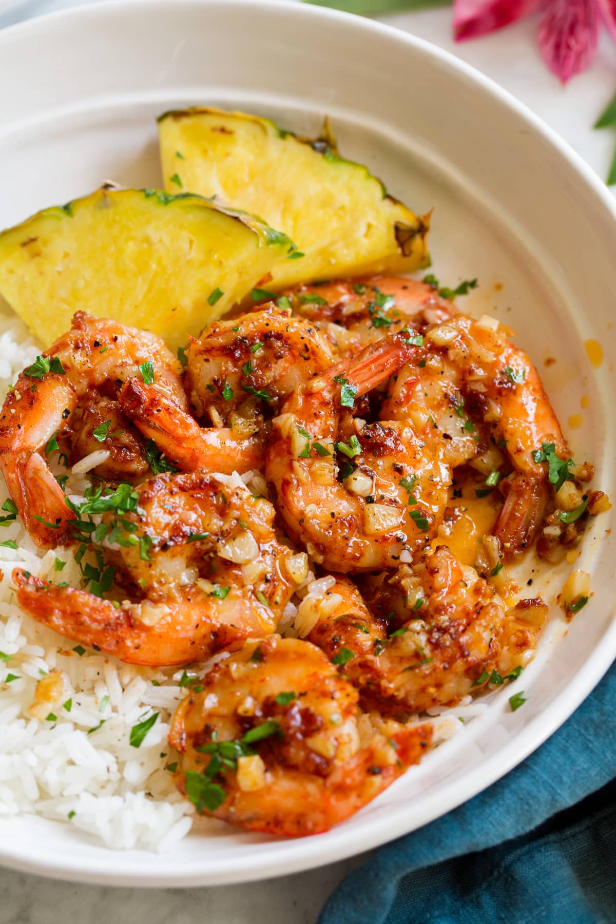 Gamberetti Hawaiani All'aglio Close up image of Hawaiian garlic shrimp served over white rice with slices of fresh pineapple.