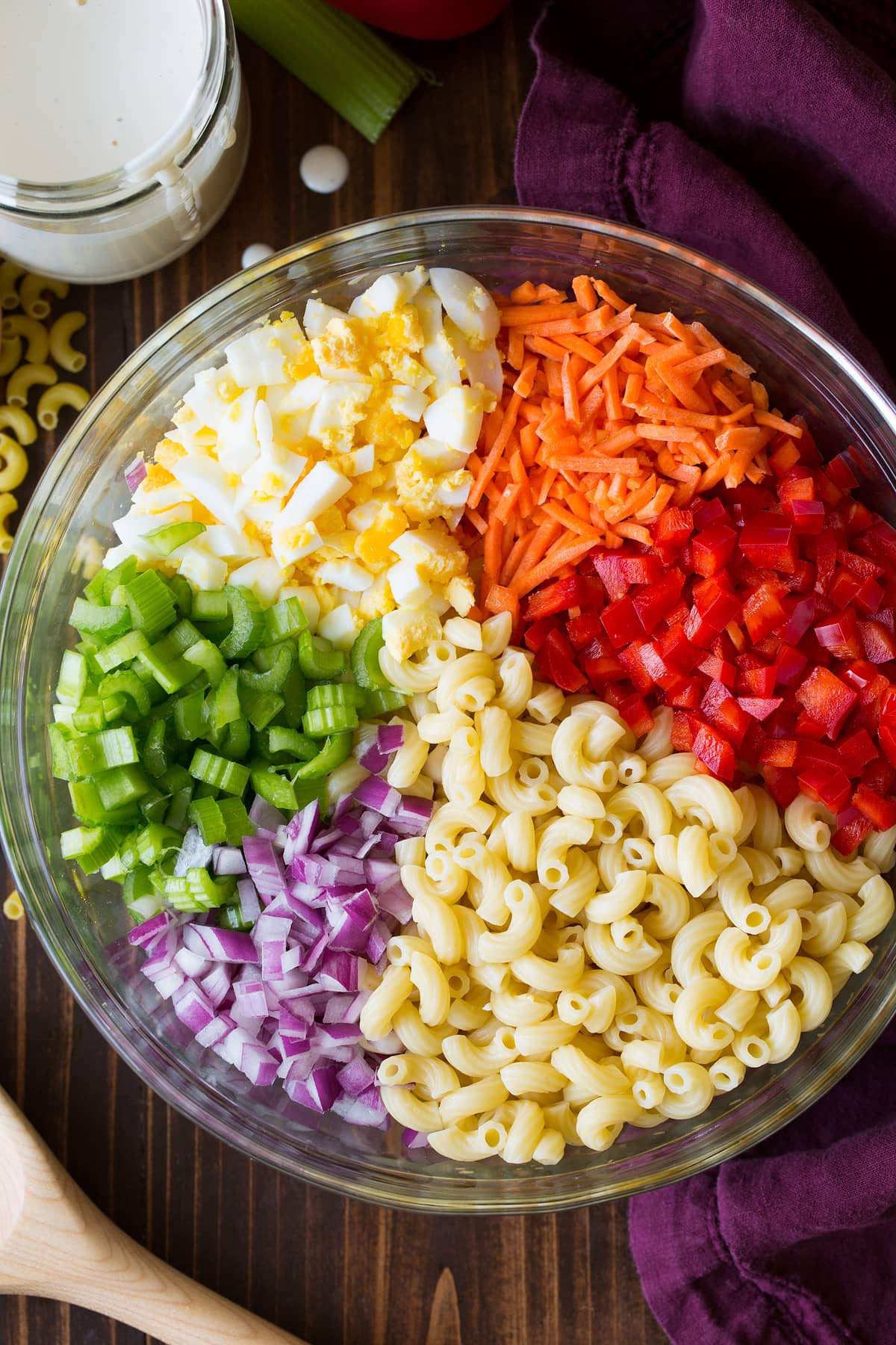 Insalata di pasta Macaroni salad ingredients in a glass bowl before tossing together.