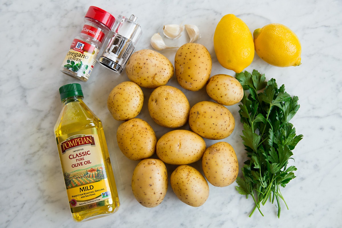 Patate Al Forno Al Limone Image of ingredients used to make lemon potatoes including yukon gold potatoes, lemons, olive oil, garlic, oregano, salt, pepper and parsley.