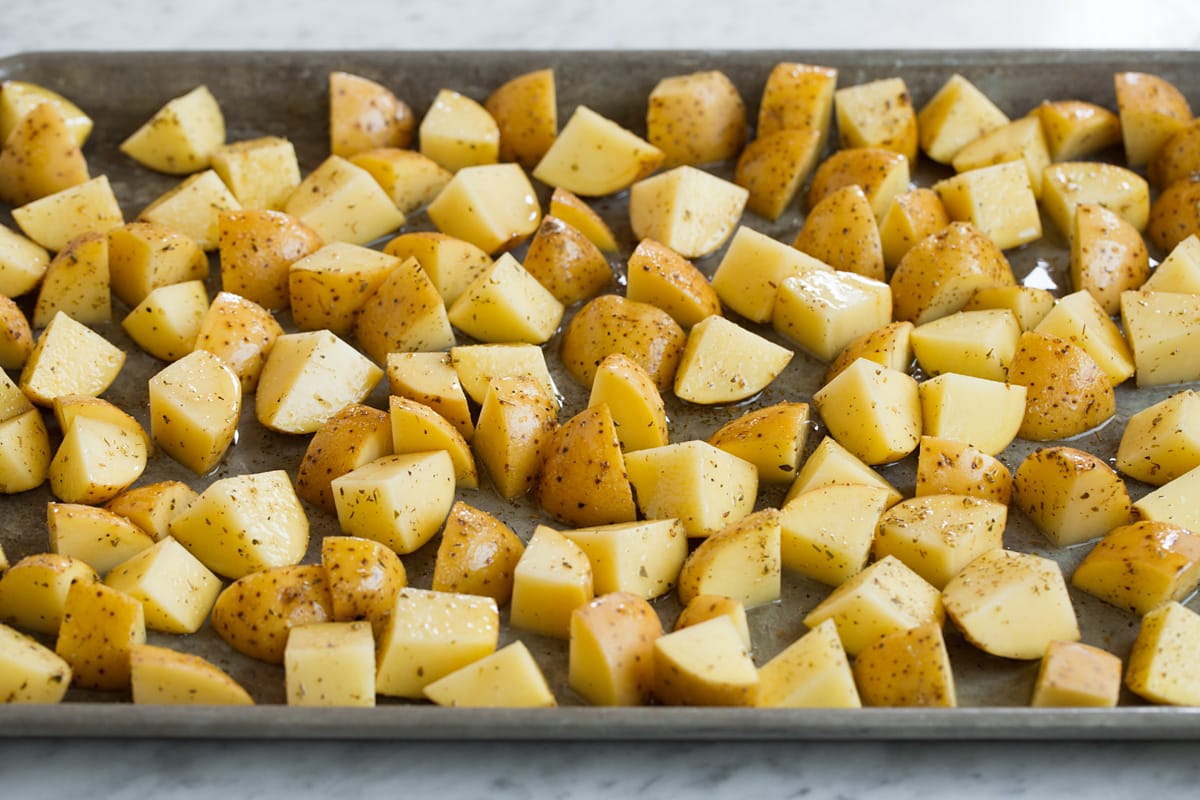 Patate Al Forno Al Limone Seasoned yukon gold potatoes spread out on a baking sheet.