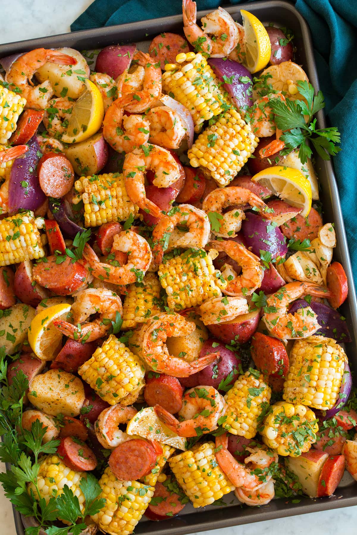 Bollire i gamberetti Image shown overhead of shrimp boil after cooking poured out and spread onto a large baking sheet.