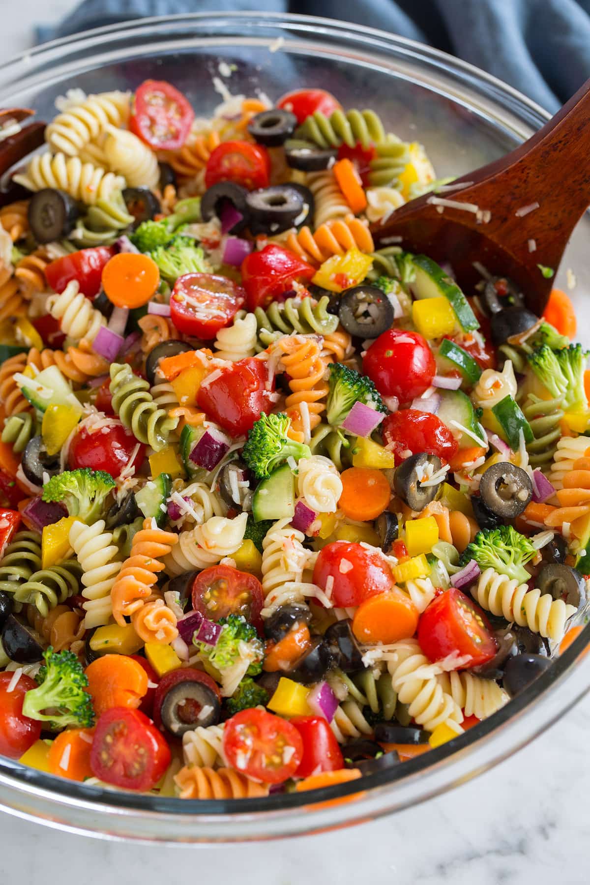insalata di pasta fredda in una ciotola di vetro con un cucchiaio di legno