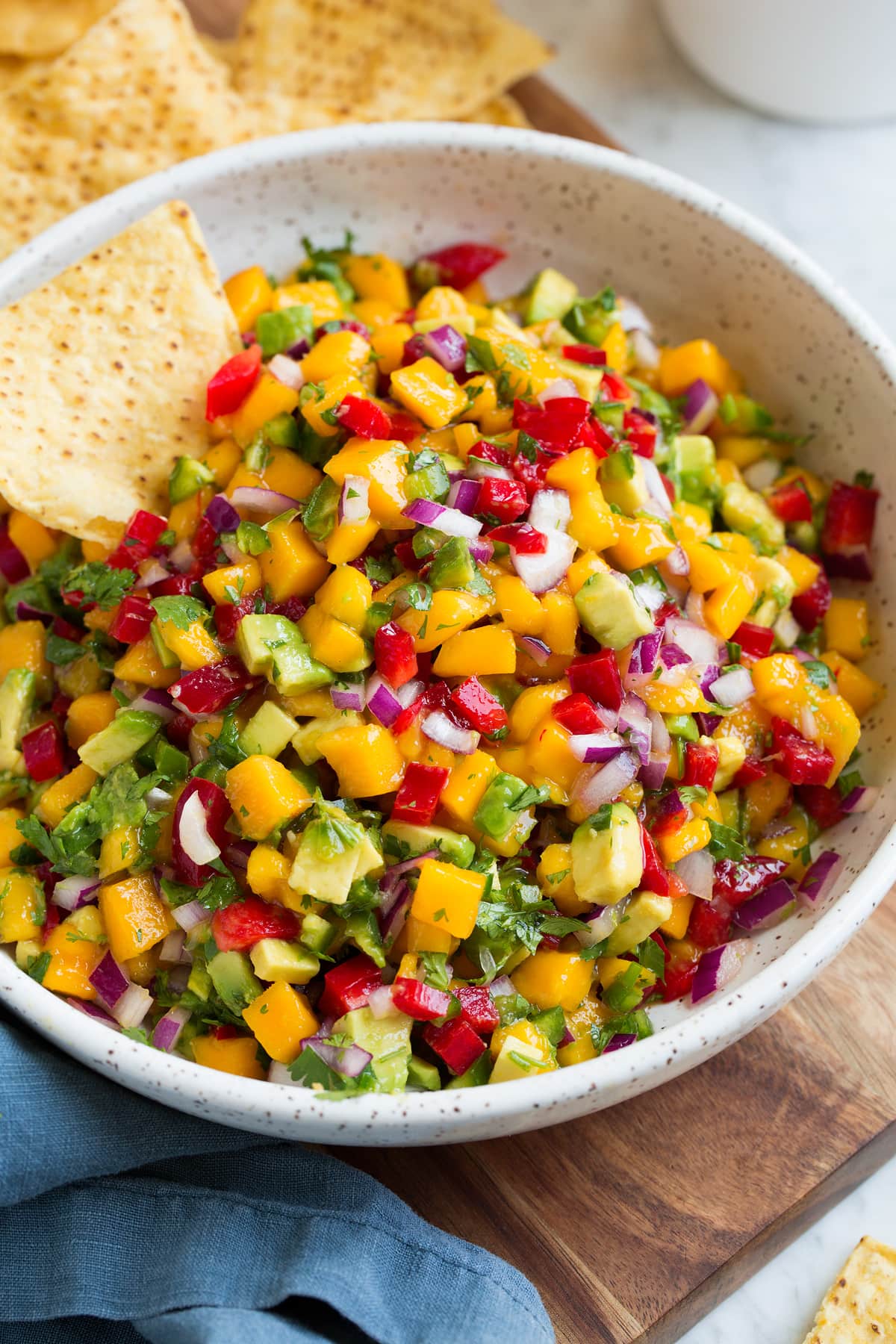 Salsa di mango (con avocado!) Bowl of mango salsa with a side of tortilla chips.