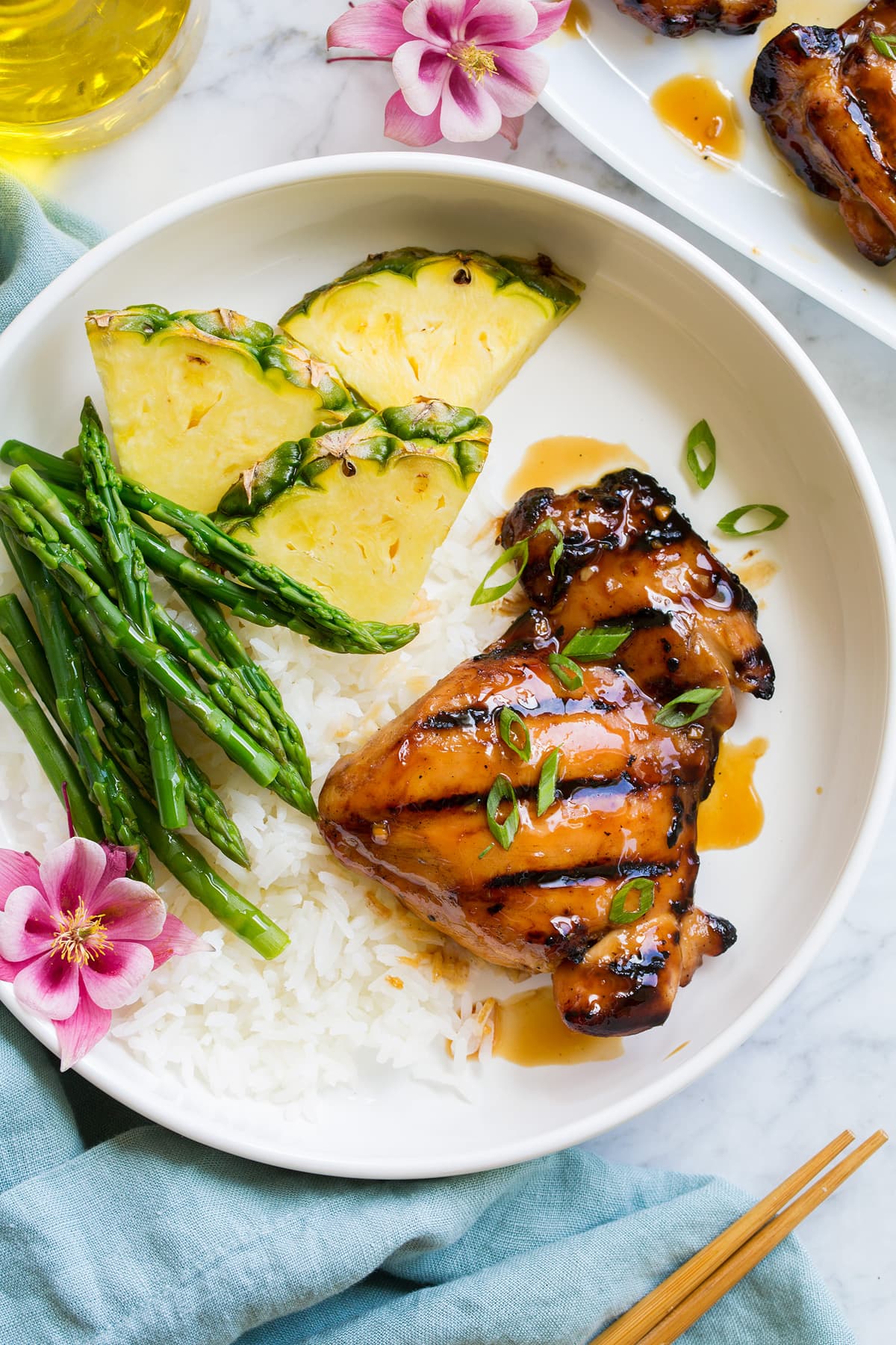 Pollo Teriyaki Alla Griglia Marinato Piece of marinated and grilled teriyaki chicken shown served with rice, asparagus and fresh pineapple.