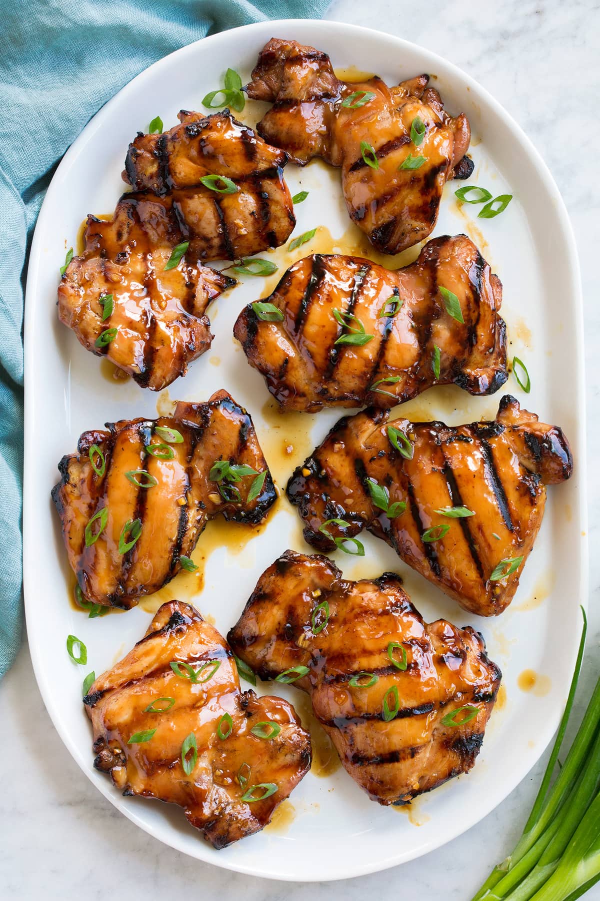 Pollo Teriyaki Marinato Alla Griglia Marinated and grilled teriyaki chicken pieces on a white serving platter, shown overhead.