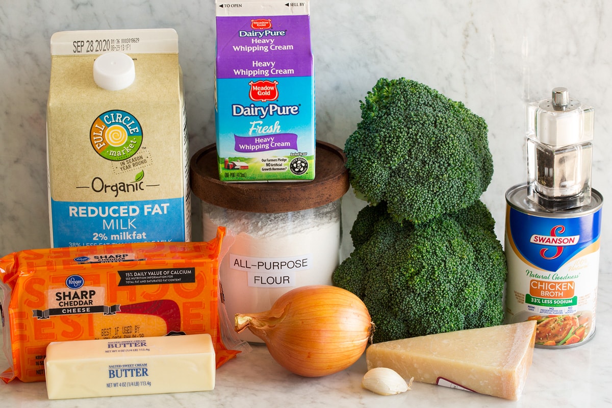 La MIGLIORE zuppa di formaggio e broccoli Image of ingredients used to make broccoli cheese soup. Shows broccoli, sharp cheddar cheese, parmesan cheese, butter, onion, garlic, flour, heavy cream, chicken broth, salt and pepper and milk.