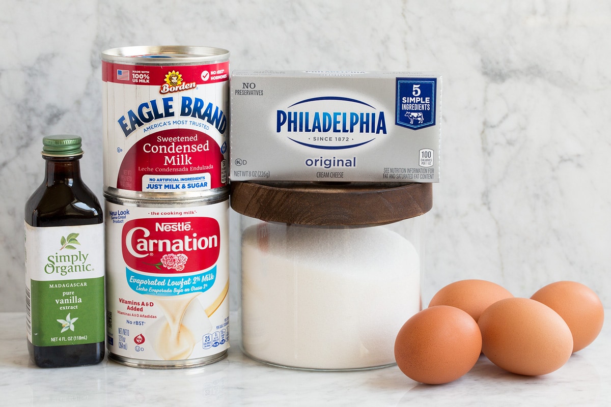 Ricetta Flan Image of ingredients used to make flan. Shows evaporated milk, sweetened condensed milk, granulated sugar, vanilla, eggs and cream cheese.