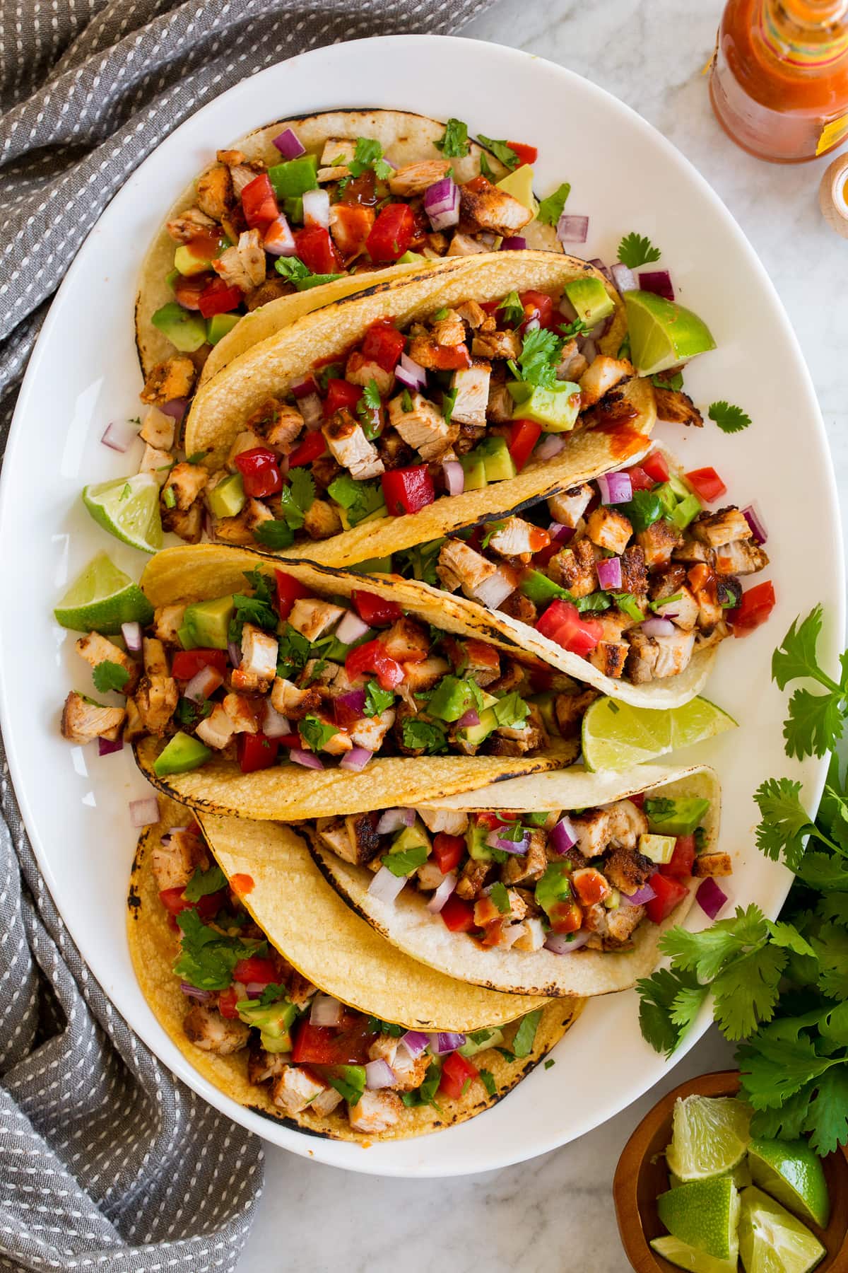 Taco di pollo Overhead image of row of six chicken tacos on a white oval serving platter.